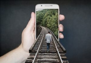 hand holding a smartphone with a picture of someone walking away with their back to us. Photo is merged so it looks like real life appears on the phone.